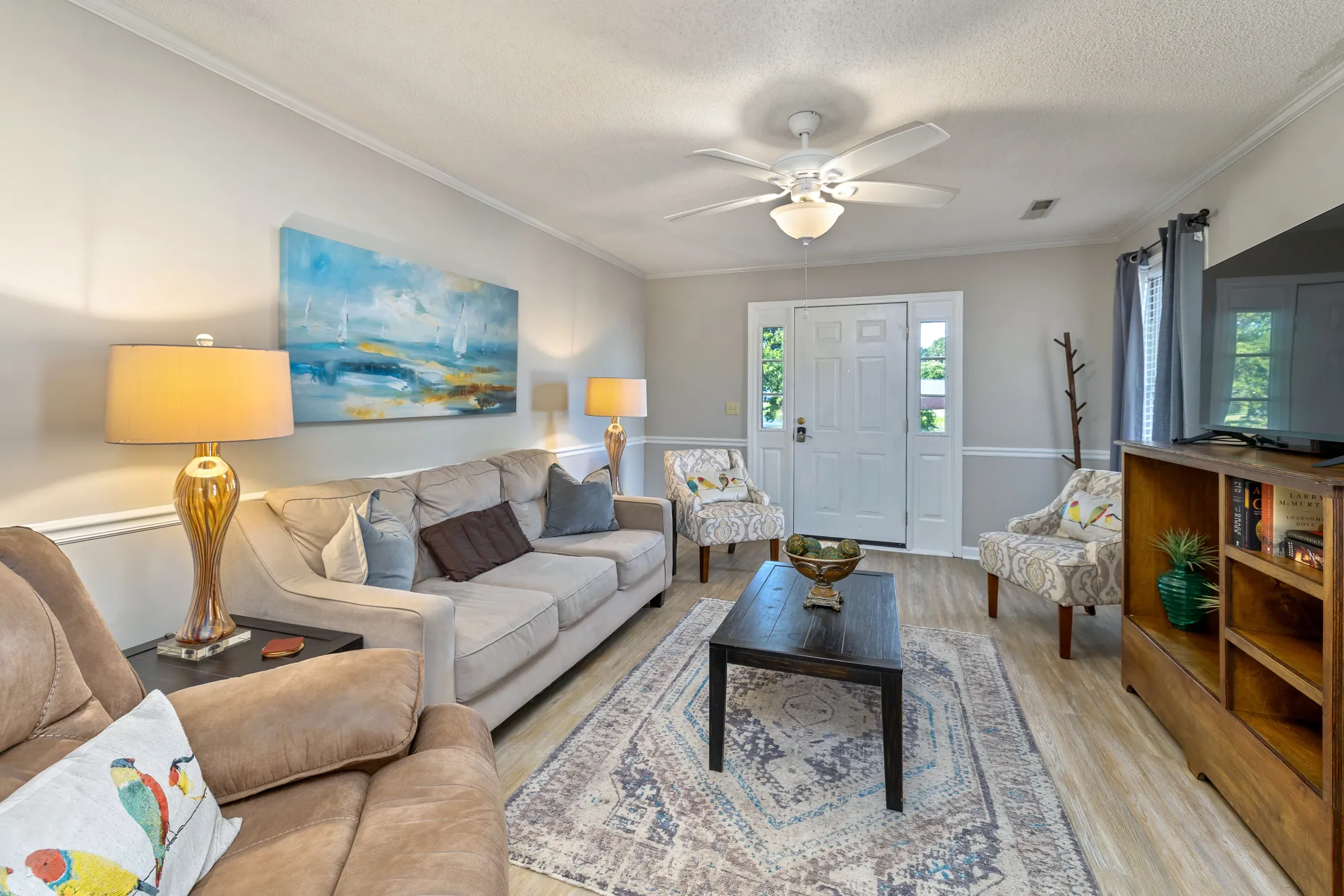 Cumberland East — bright living room with sofa and coastal art